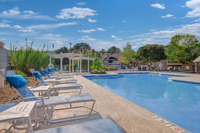 View of a white pergola with a small tree in front of it from the outdoor swimming pool at Arbors at Brookfield apartments in Mauldin, SC 